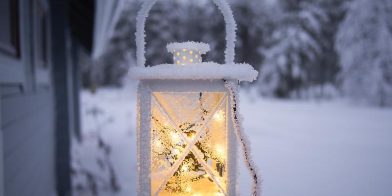 Valokuva lyhdystä. Taustalla on luminen talvimaisema. 