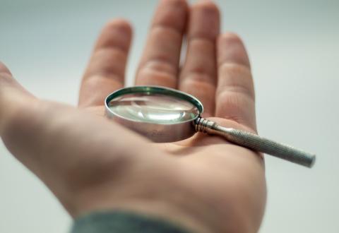 A hand holding magnifying glass