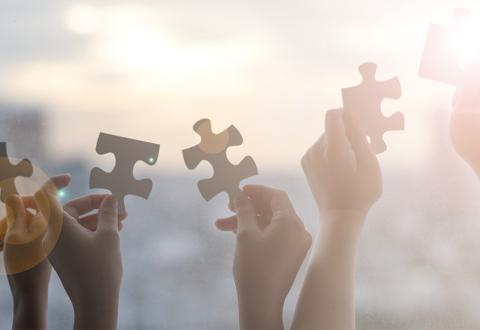 Illustrative image of several hands holding a piece of puzzle each